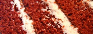 A very close shot of three layers of a red velvet cake with two layers of white cream cheese icing.