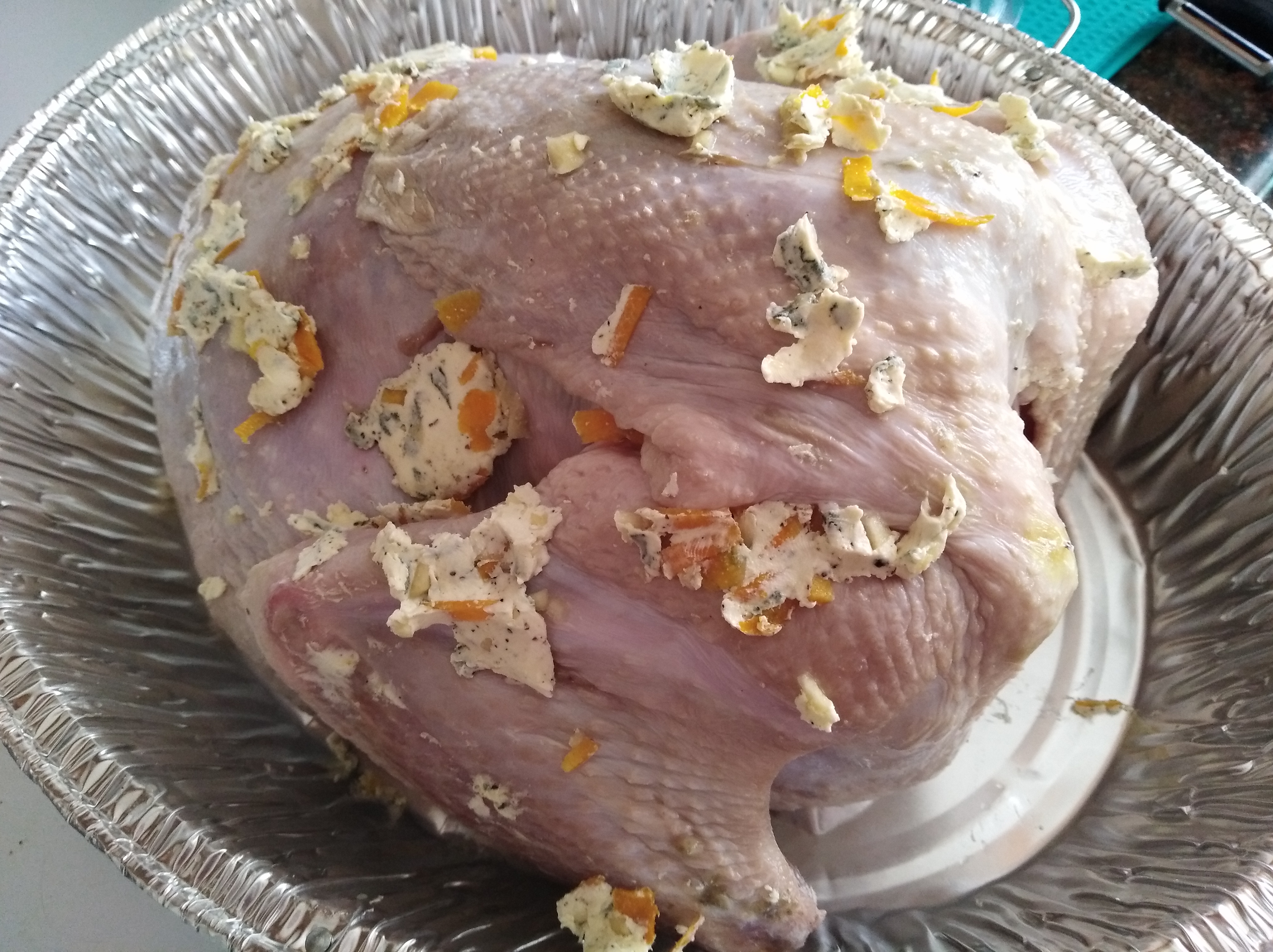 An uncooked turkey covered in butter, orange zest and sage. Not a very appealing sight.