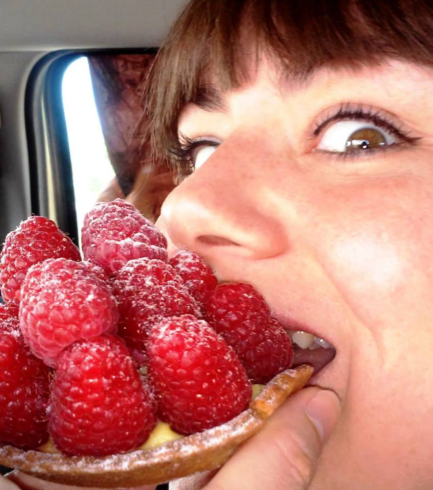 A close-up of Iris eating a raspberry tart, with a mountain of raspberries, not only a few.